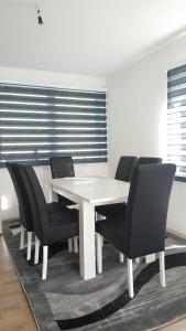 a dining room with a white table and black chairs at Apartman Košuta 2 in Tjentište