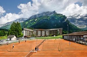 un court de tennis en face d'une montagne dans l'établissement Eurotel Victoria Les Diablerets Superior, aux Diablerets