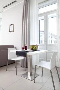 a white dining room with a table and two chairs at Palazzo Talenti 1907 in Trieste