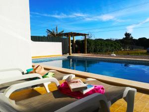 a swimming pool with a table and two chairs next to it at Quinta Das Palmeiras in Quarteira