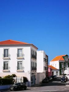 a white building with cars parked in a parking lot at Peniche's Blue & White in Peniche