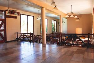 Habitación grande con suelo de madera, mesas y ventanas. en Hotel Torres del Sol en Merlo