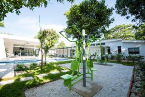 a garden with a tree and chairs in front of a building at Hotel Nicte in Managua