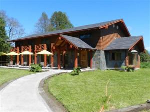 a large wooden house with a path in front of it at Hotel Boutique Ecoterraverde in Panguipulli