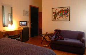 a room with a bed and a couch and a desk at Hotel Principe in Udine