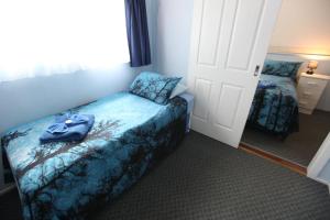 a small room with a bed and a door with a robe on it at Jacaranda Guest House in Busselton