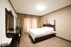 Schlafzimmer mit einem Bett, einem Schreibtisch und einem Fenster in der Unterkunft Daea Ulleung Resort in Ullŭng