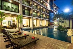 a hotel with a pool and benches in a courtyard at Royal Thai Pavilion Jomtien Hotel in Jomtien Beach