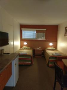 
a bedroom with two beds and a desk at Motel Monaco in Ipswich
