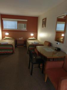 
a hotel room with two beds and a table at Motel Monaco in Ipswich
