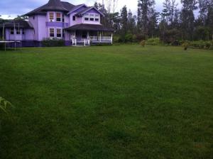 a purple house with a large field of green grass at Hawaii Tropical Volcano mansion + Sauna in Hilo