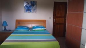 Dormitorio con cama colorida y cabecero de madera en Haut de villa, en Sainte-Rose
