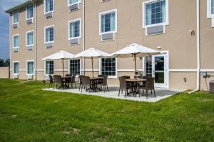 a patio with tables and umbrellas in front of a building at Cobblestone Inn & Suites - Vinton, LA in Vinton