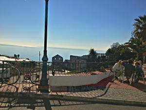a group of people sitting in chairs next to a fence at Apartamentos Balcón de Maro in Maro