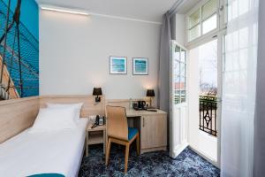a hotel room with a bed and a desk and a window at Hotel Eureka in Sopot