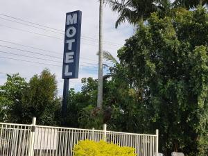 a street sign on a pole in front of a palm tree at Kipparing Village Motel in Redcliffe