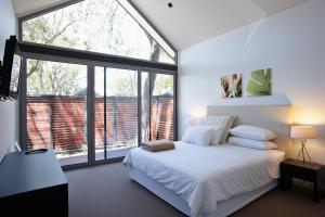 a bedroom with a white bed and a large window at Aqua Resort Busselton in Busselton