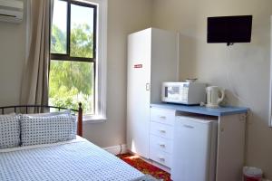 a bedroom with a bed and a microwave on a counter at Ithaca 1896 Manor in Busselton