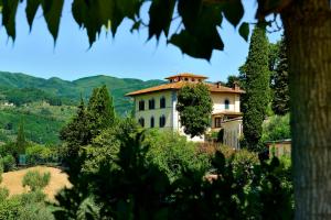 ein Haus auf einem Hügel mit Bäumen im Vordergrund in der Unterkunft Villa Parri Residenza D'epoca in Pistoia
