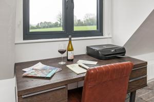 einen Schreibtisch mit einer Flasche Wein und einem Glas in der Unterkunft Paddock View in Winchester
