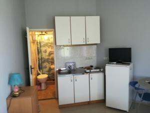 cocina con armarios blancos y nevera en Apartmani Filipovic, en Kladovo