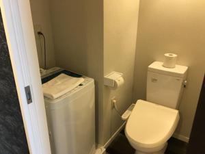 a small bathroom with a toilet and a roll of toilet paper at Mr KINJO in 西原インター in Ginowan