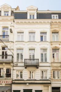 a tall white building with windows and balconies at Urban Suites Brussels Royal in Brussels