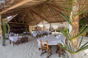 un restaurante con mesas y sillas blancas y techo de madera en Le Zahir de l'ile - Iranja, en Nosy Be