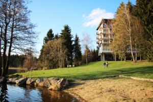 dwoje ludzi stojących przed budynkiem obok rzeki w obiekcie Hotel Medlov Depandance w mieście Fryšava