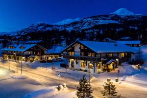 a lodge in the snow at night with snow covered mountains at Hemsetunet Apartments in Hemsedal