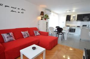 a living room with a red couch and a kitchen at Apartman Terzić in Rovinj