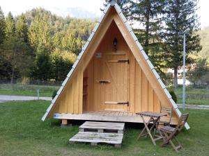 ein kleines Holzhaus mit einem Tisch und einem Stuhl in der Unterkunft Camp Podljubelj in Podljubelj