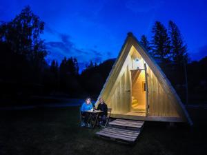 zwei Menschen sitzen an einem Tisch vor einem winzigen Haus in der Unterkunft Camp Podljubelj in Podljubelj