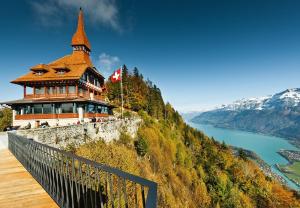 un edificio sul fianco di una montagna con un lago di Residence Villa Flora a Interlaken