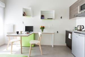 Il comprend une cuisine avec une table, des chaises et un bureau. dans l'établissement L'Aéronat by Popinns, à Saint-Cyr-lʼÉcole