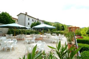 a patio with white tables and chairs and umbrellas at Albergo Sapori in Tolè
