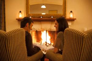 a man and a woman sitting in chairs in front of a fireplace at Browns Boutique Hotel in Queenstown