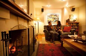 2 personas sentadas en un sofá en una sala de estar con chimenea en Browns Boutique Hotel, en Queenstown