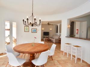 a dining room with a wooden table and white chairs at Villa Sa Seni in Cala Llonga