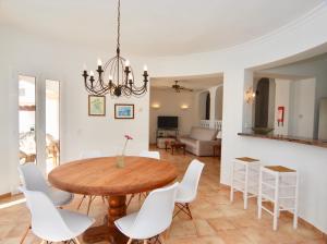 una sala da pranzo con tavolo in legno e sedie bianche di Villa Sa Seni a Cala Llonga