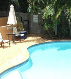 a large swimming pool with a table and a chair at Meridian Caloundra in Caloundra