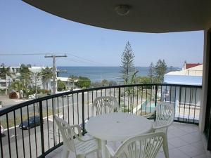 a white table and chairs on a balcony with the ocean at Meridian Caloundra in Caloundra