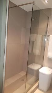 a glass shower in a bathroom with a toilet at Elegant Apartment at Grove Mall in Windhoek