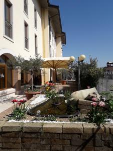 a fountain in front of a building with an umbrella at Hotel Scaligero in Sommacampagna