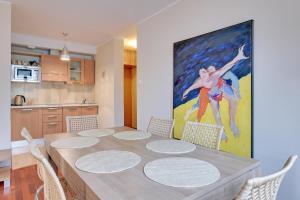 a dining room table with chairs and a painting on the wall at Apartamenty Apartinfo Na Wydmie in Jurata
