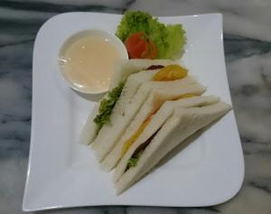 um prato branco com uma sanduíche e vegetais sobre ele em Grand Cepu Hotel em Cepu