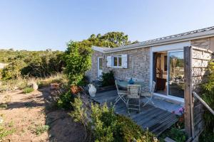 a small house with a wooden deck with a table at Chalet Valle di Corti in Pianottoli-Caldarello