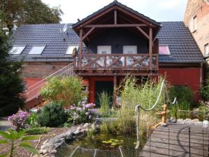 ein Haus mit einem Teich vor einem Gebäude in der Unterkunft Urlaubsscheune in Niedergörsdorf