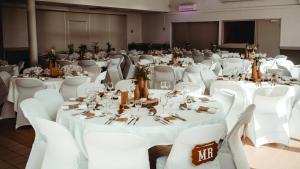 a banquet hall with white tables and white chairs at Village Beauséjour - Rêves de mer in Le Conquet