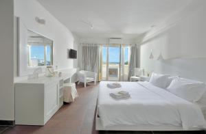 a white bedroom with a white bed and a bathroom at Jenny's Summer Houses in Platis Yialos Mykonos